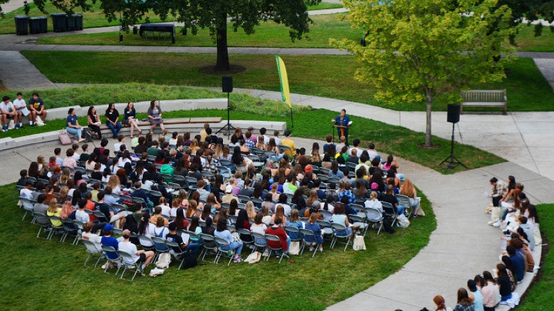 overhead view of a large gathering of students in an oval lawn.