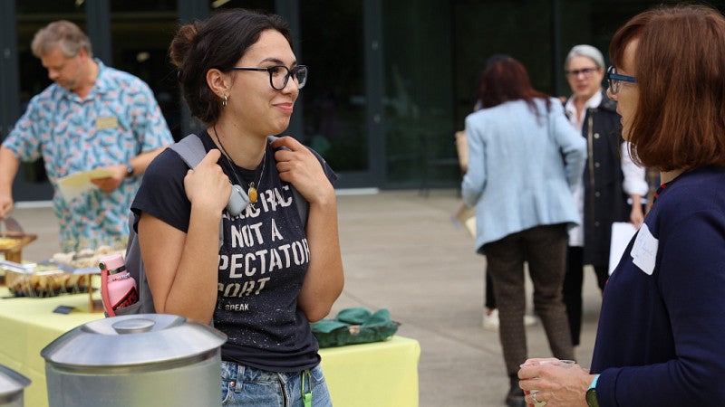 A student with a backpack listens to a professor.