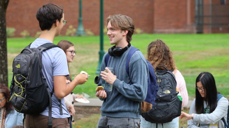 Two students chat on the edge of Tykeson-Chapman lawn