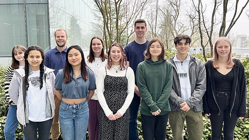 group of 10 students posing outside the Knight Campus building on a gray day