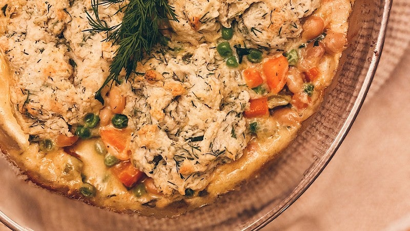 a chicken pot pie with a biscuit top and a dill sprig on top