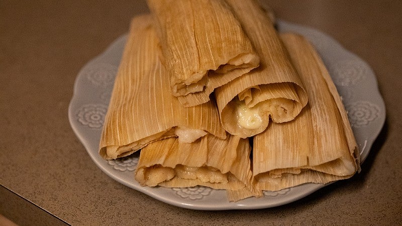 a plate of tamales with cheese oozing out of the tops