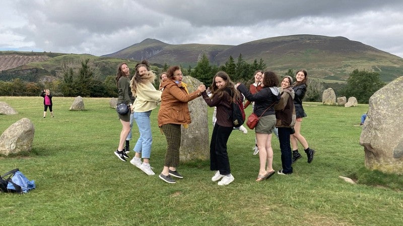 group of people circling around a standing stone in the oxford countryside