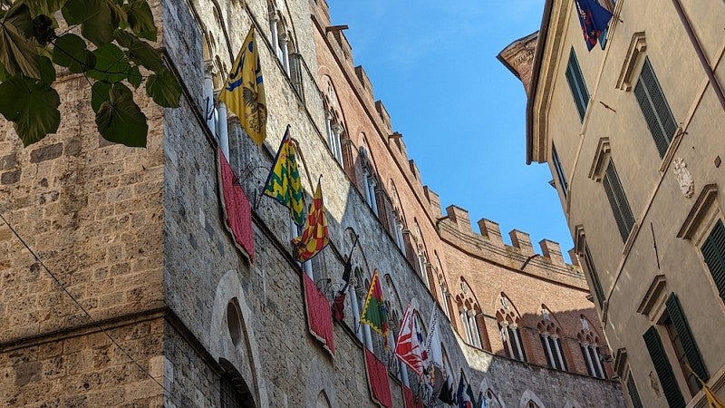 street scene in siena with old buildings and colorful flags