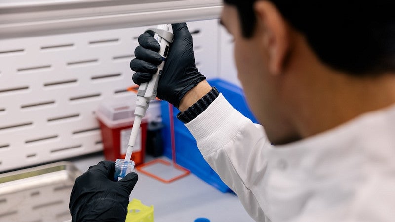 person using pipette in lab fume hood