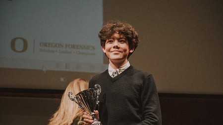 Student at a Forensics Event holding a trophy.