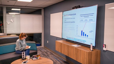 Student watching conference on screen