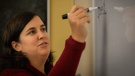 Nicole Dudukovic writes on a whiteboard during class