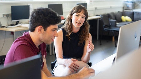 Ella Hutcherson (right) speaks with a student colleague in a computer lab.