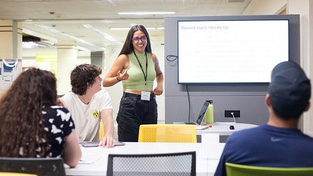 Megan Rangel-Lynch (2023) stands in front of a screen as she gives a presentation.