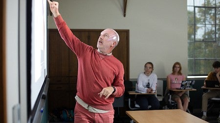 christopher michlig pointing at the board as he teaches a class