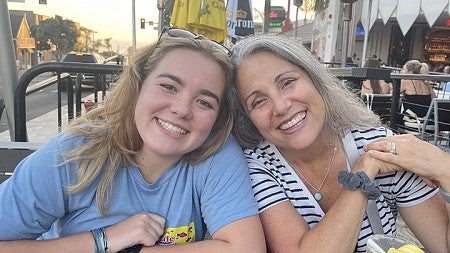 hannah landswick posing with family member at outdoor restaurant table on street