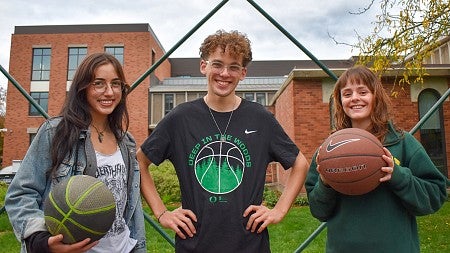 three student leaders of the firegen collaborative pose under an outdoor basketball hoop on the UO campus