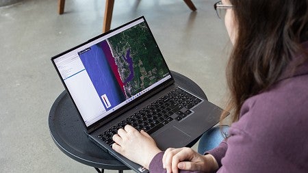 looking over a student's shoulder at their laptop screen, showing a visualization of the west coast with tsunami intensity indicated in red