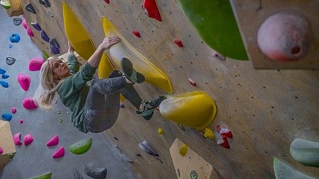 person on climbing wall overhang with colorful grips 