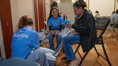 volunteers helping community member with medical device