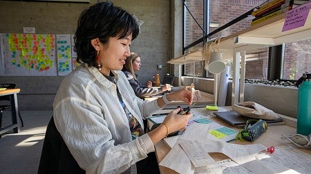 student at studio desk, cutting materials