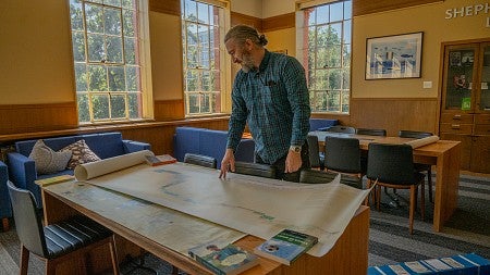 Marcel Brousseau standing over a table of large maps in the Chapman Hall Library