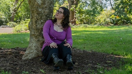 sierra matz seated against a tree trunk in a park