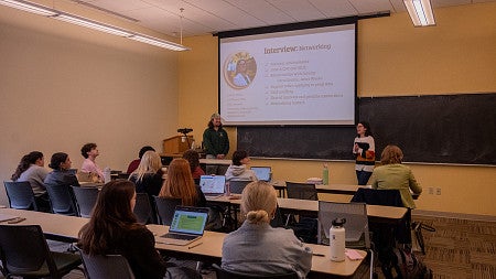 classroom of students watching two students present slides