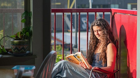 student reading on apartment balcony