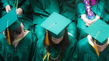 Birdseye view of graduates in green gowns and mortarboard caps.