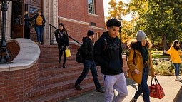 students walking down chapman hall exterior stairs into fall morning light