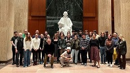 tour group of students posing in front of statue at library of congress