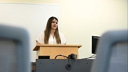 student at podium, speaking to empty classroom