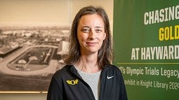 photo of lauren goss in front of Knight Library exhibit on Hayward Field