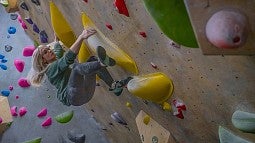 person on climbing wall overhang with colorful grips 
