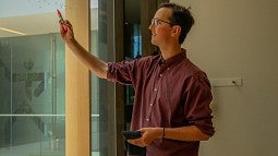 student writing equation on glass with marker