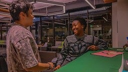 two students talking at table in campus building
