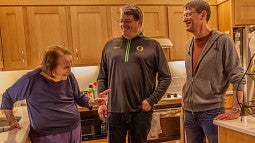 fred poust with his mother joy and brother alex in a kitchen