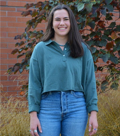 Bella Albiani standing in front of a brick building's landscaping