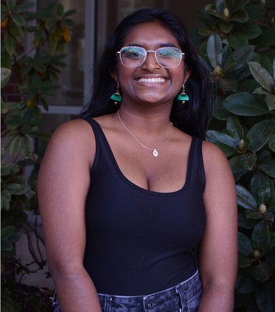 Tarini Ramasamy smiles in front of lush vegitation