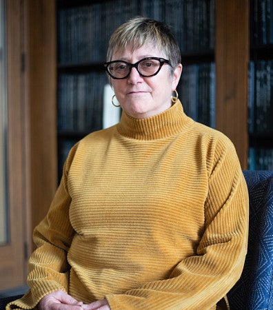 Carol Stabile seated in front of a shelf of bound theses.