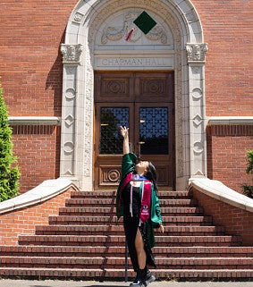 Grace Miyoshi (2023) tosses her graduation cap into the air in front of Chapman Hall.