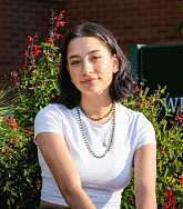 Kali deSaint Phale sitting in front of the William W Knight Law Center