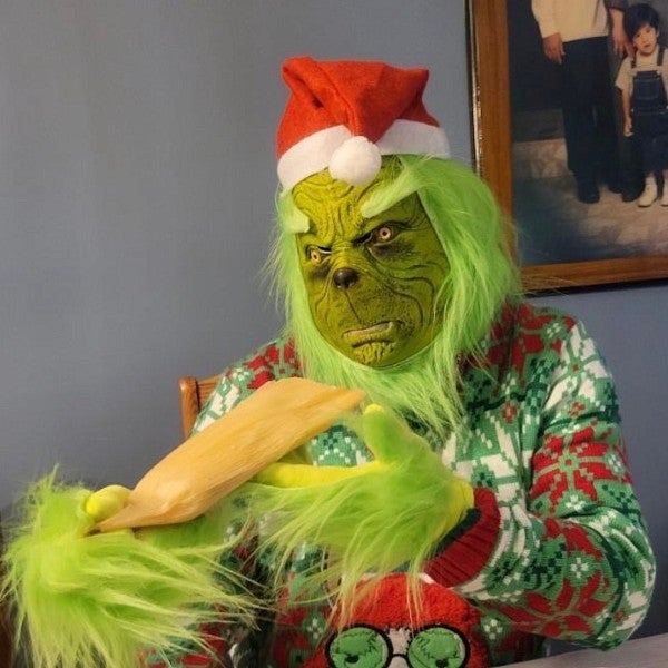 a person dressed as the grinch who stole christmas eating a plate of tamales