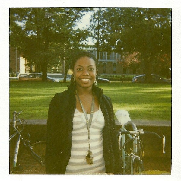 ann oluloro poses on the UO campus in front of a bike rack and grassy lawn