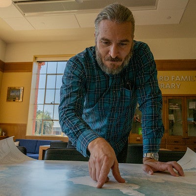 marcel brousseau pointing at a map on a table in Chapman library