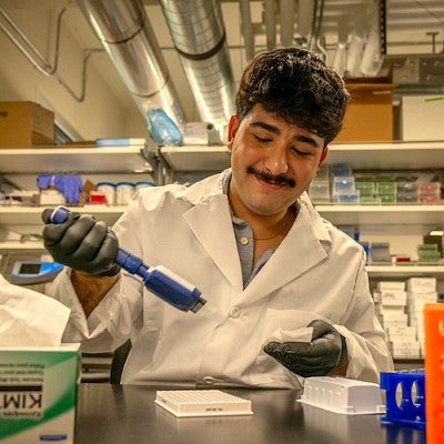 student using pipette at lab bench