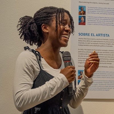 student speaking into mic and smiling in museum gallery