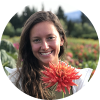 circular portrait of angela pelky holding a dahlia in a field of flowers