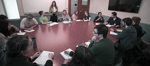 Students seated around an oval table with composition books open.