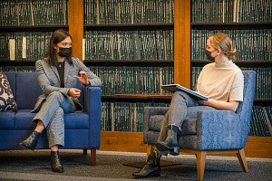 Two women, masked against COVID and socially distanced, discuss in the the Clark Honors College thesis library.
