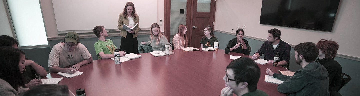 Students seated around an oval table with composition books open.