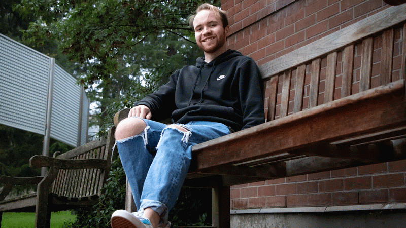Riley Hoerner sitting on a bench in front of a brick façade.