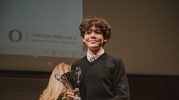 Student at a Forensics Event holding a trophy.